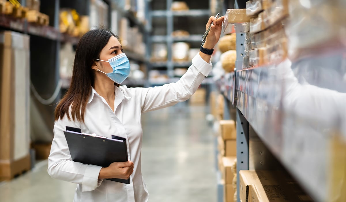 Woman in face mask checking warehouse inventory