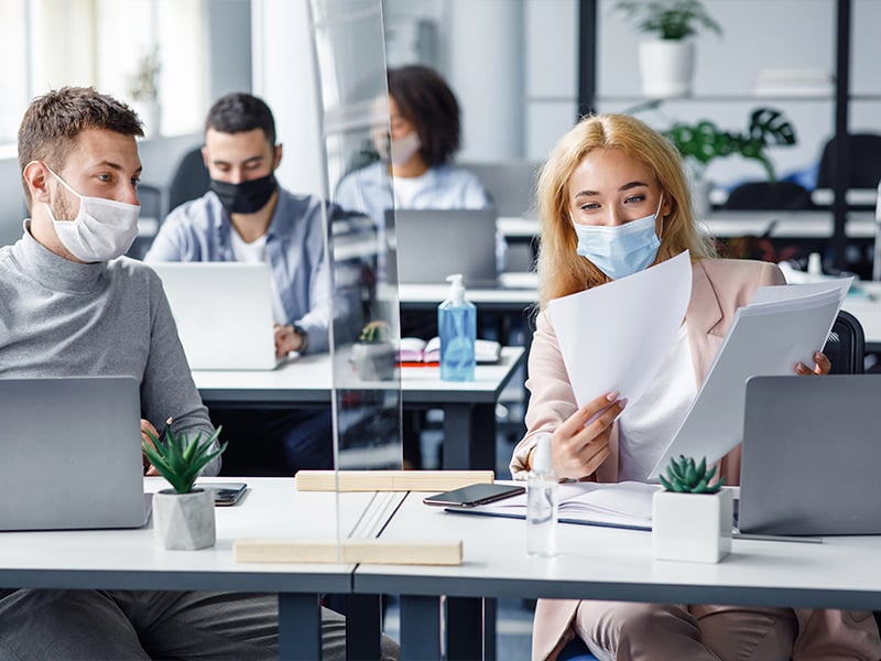 Office employees reviewing paperwork with face masks