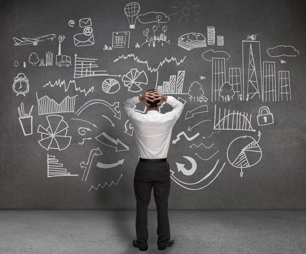 Stressed businessman looking at drawings of charts and sketches on a wall-1